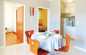 A dining area with a round table, four chairs, and a kitchen in the background. - Stunning apartment in Rabac with WiFi (Rabac)