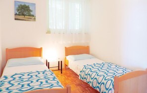 A bedroom with two single beds, a nightstand, a lamp, and a painting on the wall. - Stunning apartment in Rabac with WiFi (Rabac)
