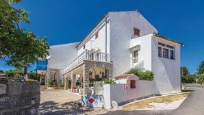 A traditional white building with a balcony, stone archways, and a small garden area. - Nice apartment in Porec with WiFi (Porec)