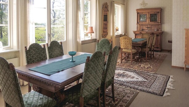 A dining room with a wooden table and chairs, a chandelier, and a view of the outdoors through large windows. - Lovely home in älmhult with kitchen (Älmhult)