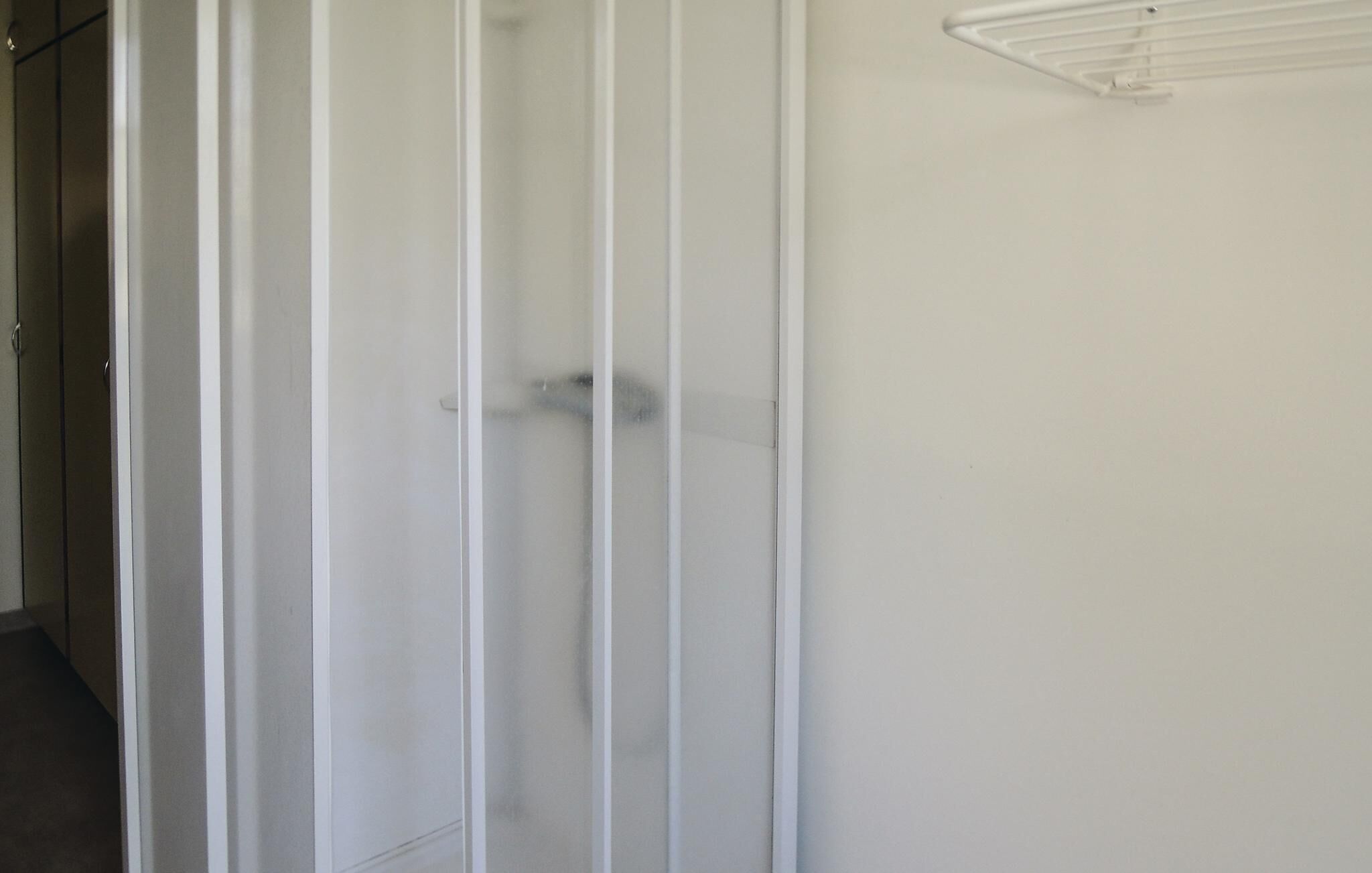 Una habitación blanca con una puerta y un toallero blanco.