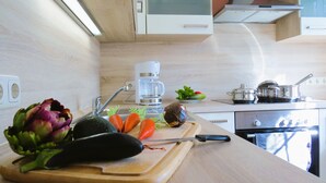 Une cuisine avec un plan de travail en bois, une machine à café, une cuisinière et divers légumes.
