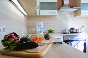 A kitchen with a wooden countertop, a coffee maker, a stove, and various vegetables.