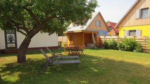 Une maison en bois avec un patio, un arbre et une pelouse.