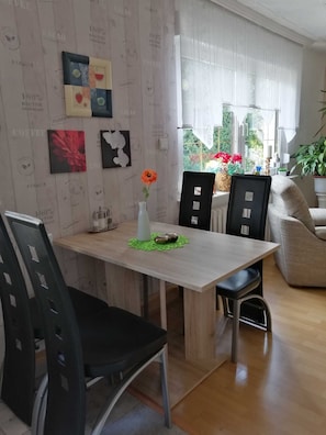 Un comedor moderno con una mesa de madera, sillas negras y un jarrón con una flor.