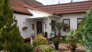 A house with a tiled roof, a front door, and a small garden with various plants and flowers. - Vacation apartment Lotti, Germany (Lutherstadt Wittenberg)