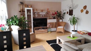 A living room with a TV, wooden furniture, a bookshelf, and various decorative items. - Vacation apartment Lotti, Germany (Lutherstadt Wittenberg)
