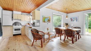 Une cuisine moderne avec des meubles en bois, une cuisinière et un coin repas comprenant des chaises et une table en osier.