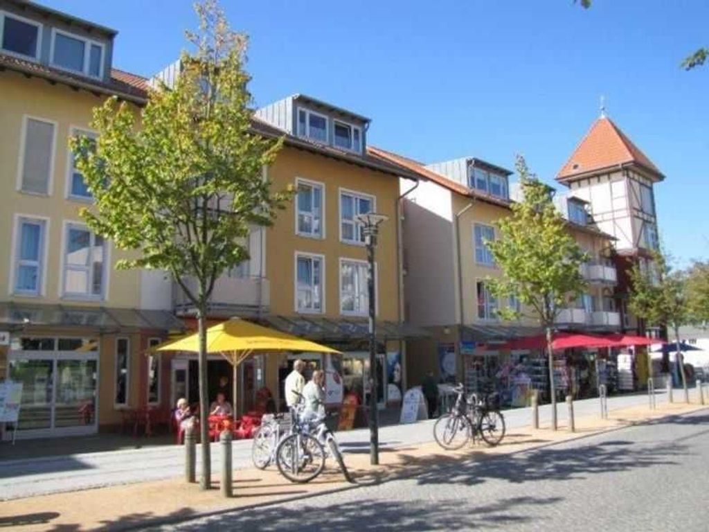 A street with buildings, outdoor seating, and bicycles.
