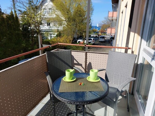 A balcony with a round table, two chairs, and two green cups.
