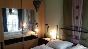 Una camera da letto con un letto, un comodino, uno specchio e una finestra con tende.
