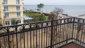 Un edificio giallo con molte finestre e balconi, un giardino curato con un vialetto circolare e vista sul mare.