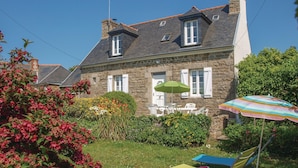 Ein Steinhaus mit Garten, Sitzgelegenheiten im Freien und einem grünen Sonnenschirm.