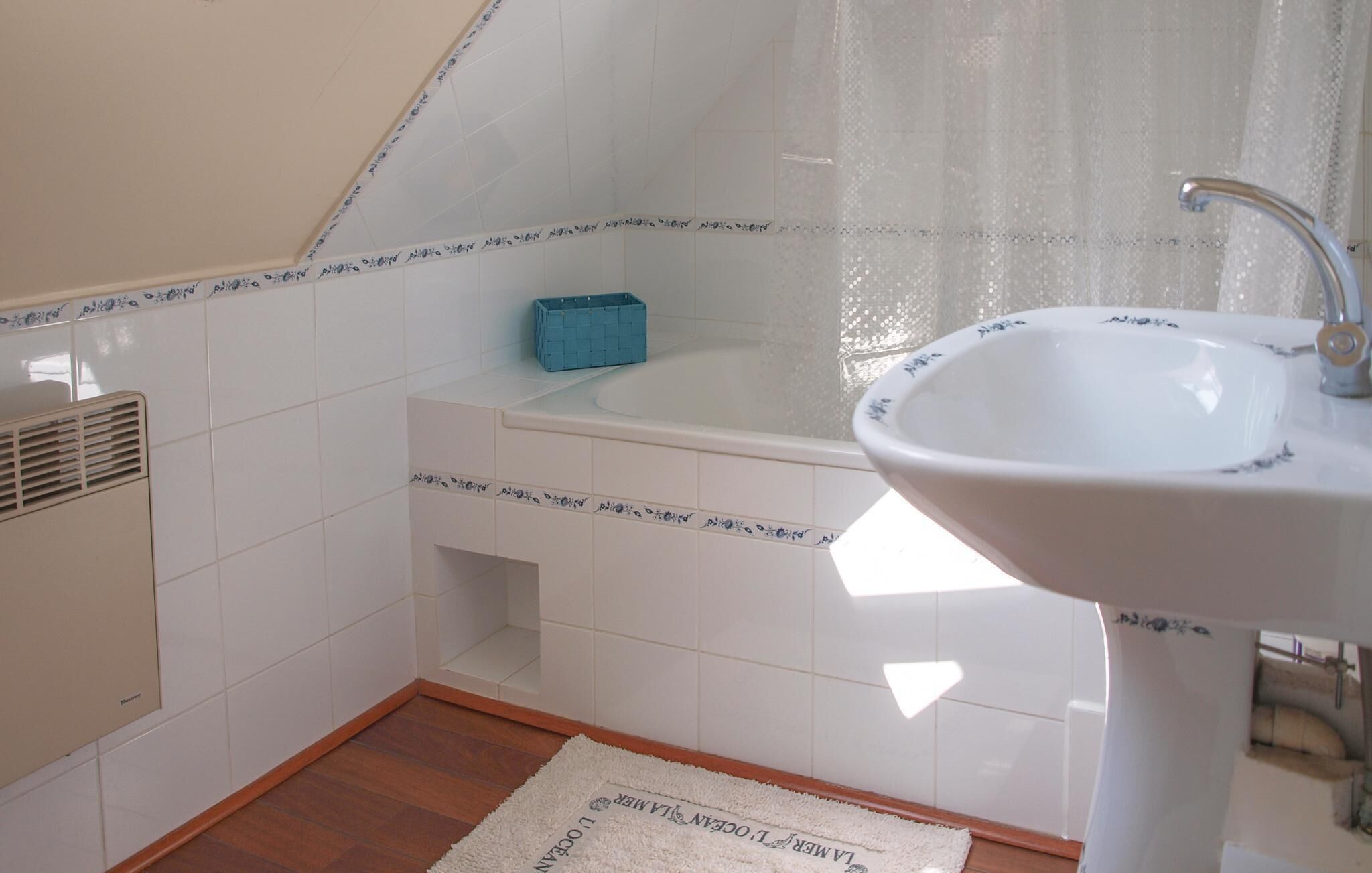 Un baño con lavamanos blanco, bañera y cortina de ducha.