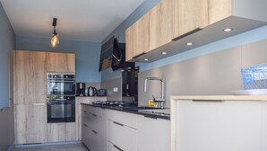 Eine moderne Küche mit Holzausstattung, Edelstahlgeräten und einer schwarzen Arbeitsplatte.
