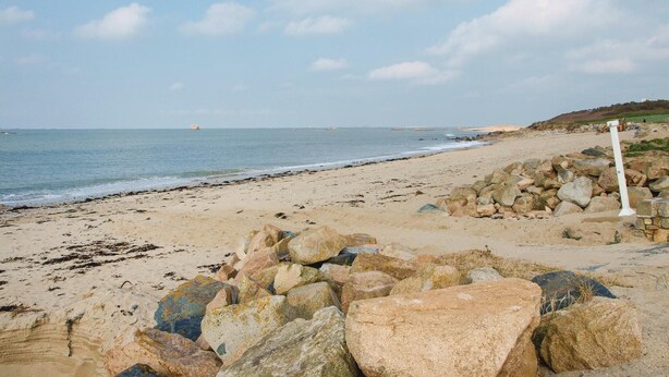Ein Strand mit felsigem Ufer und blauem Himmel.