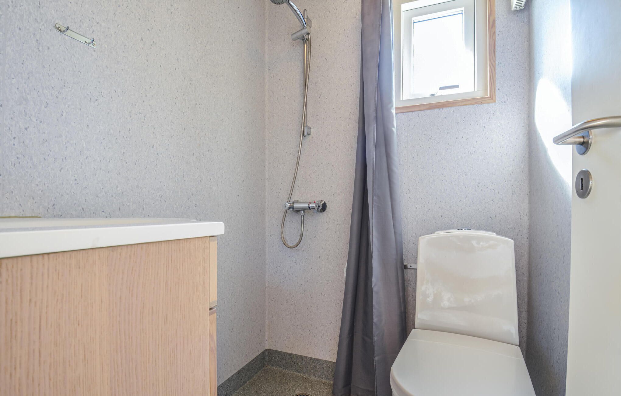 Un baño con ducha, inodoro y ventana.