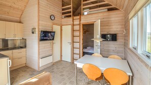 Una compatta casetta in legno con angolo cottura, zona pranzo e soppalco.