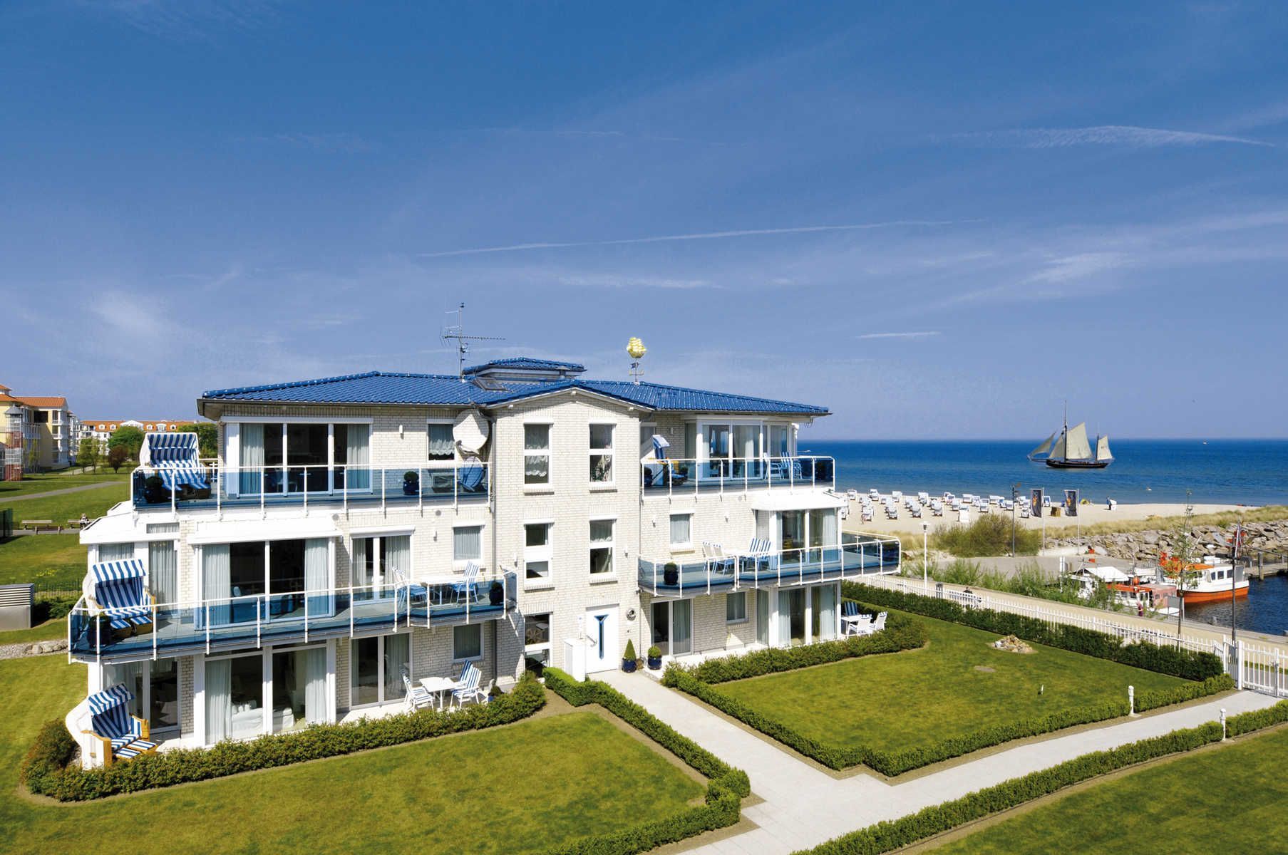 Ein mehrstöckiges Hotel mit Balkonen, Blick auf den Strand und einem Segelboot in der Ferne.