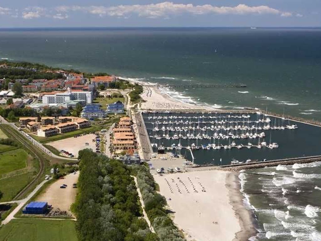 Eine Luftaufnahme einer Küstenlandschaft mit einer Marina, einem Strand und Gebäuden.