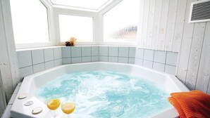 Un jacuzzi con dos vasos de jugo de naranja, una toalla y una ventana con vistas.