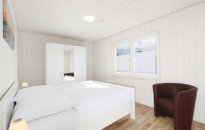 A bedroom with a bed, a chair, a window, and a wardrobe. - Pet friendly home in OstseeResort Olpenitz with sauna (OstseeResort Olpenitz)