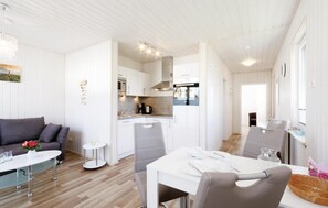 A modern, open-plan living and dining area with a kitchen, grey upholstered furniture, and a white dining table set for four. - Pet friendly home in OstseeResort Olpenitz with sauna (OstseeResort Olpenitz)