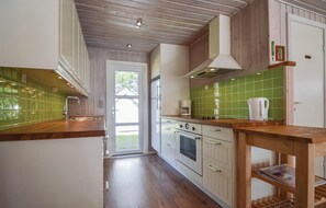 A kitchen with wooden cabinets, a green tiled backsplash, and a wooden countertop. - Cozy home in Rømø with WiFi (Rømø)