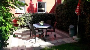A patio with a table and chairs, a potted plant, and a flag.