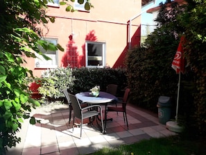 A patio with a table and chairs, a potted plant, and a flag.