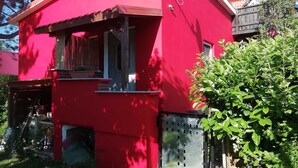 A red building with a small window, a satellite dish, and a metal gate.