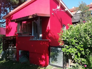A red building with a small window, a satellite dish, and a metal gate.