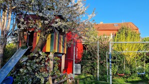 Une aire de jeux avec un toboggan, des balançoires et une maison de jeux colorée.
