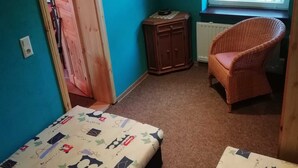 A room with two beds, a window with a view, a chair, and a radiator.