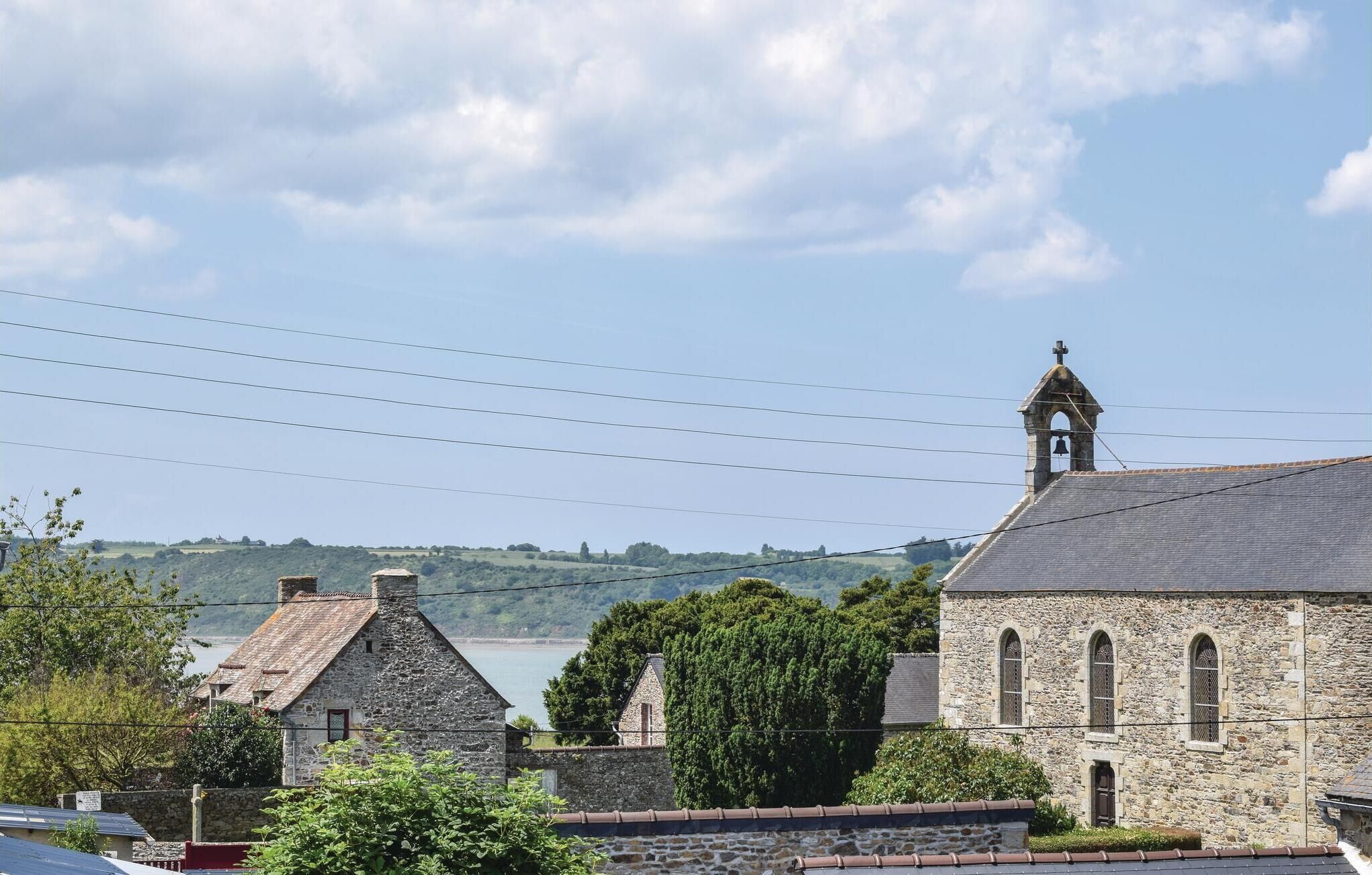 Un bâtiment en pierre doté d’un clocher, vraisemblablement une église, avec une vue sur un lac et des collines en arrière-plan.