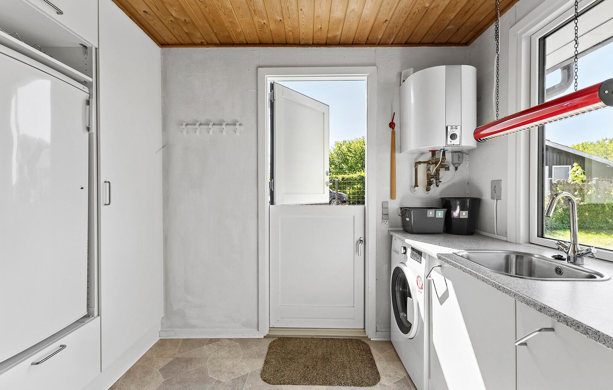Une cuisine compacte équipée d’un lave-linge, d’un évier et d’un chauffe-eau.