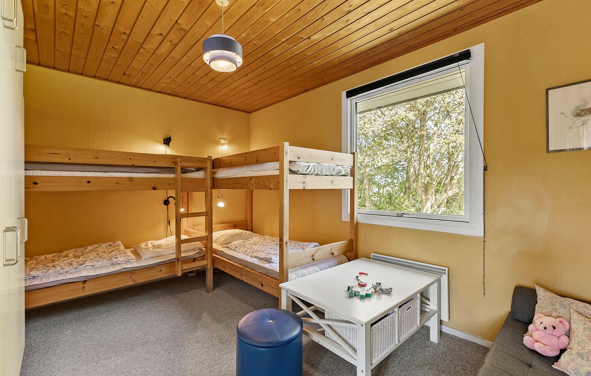 Ein Schlafraum mit Etagenbetten, einem Tisch und einem Fenster.