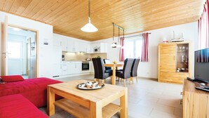 Un salon moderne avec une table à manger en bois, un canapé rouge et une cuisine en arrière-plan.