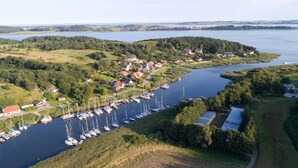 An aerial view of a lakeside village with a marina, houses, and surrounding greenery. - Sun view with sun terrace 5 min to the Baltic Sea and beach (Sellin)