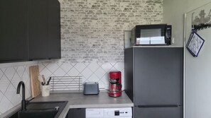 Une cuisine équipée d’un four à micro-ondes, d’un grille-pain et d’une machine à café sur le plan de travail, ainsi que d’un évier et d’un lave-vaisselle.