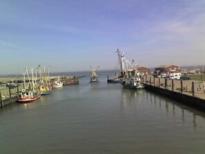 A harbor with boats docked, a pier, and a building in the background. - North Sea House Dornumersiel - house (Dornum)