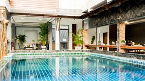 A swimming pool with a tiled edge, surrounded by potted plants and a wooden deck. - Baan Chankaew Hotel (Ko Pha-ngan)
