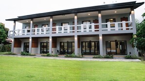 A two-story building with a balcony, large windows, and a well-maintained lawn. - Baan Chankaew Hotel (Ko Pha-ngan)