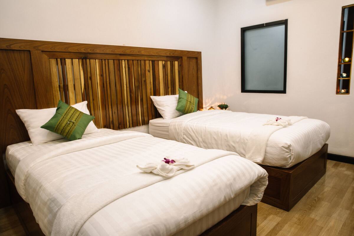 Una habitación de hotel con dos camas, cabeceros de madera y un espejo enmarcado en la pared.