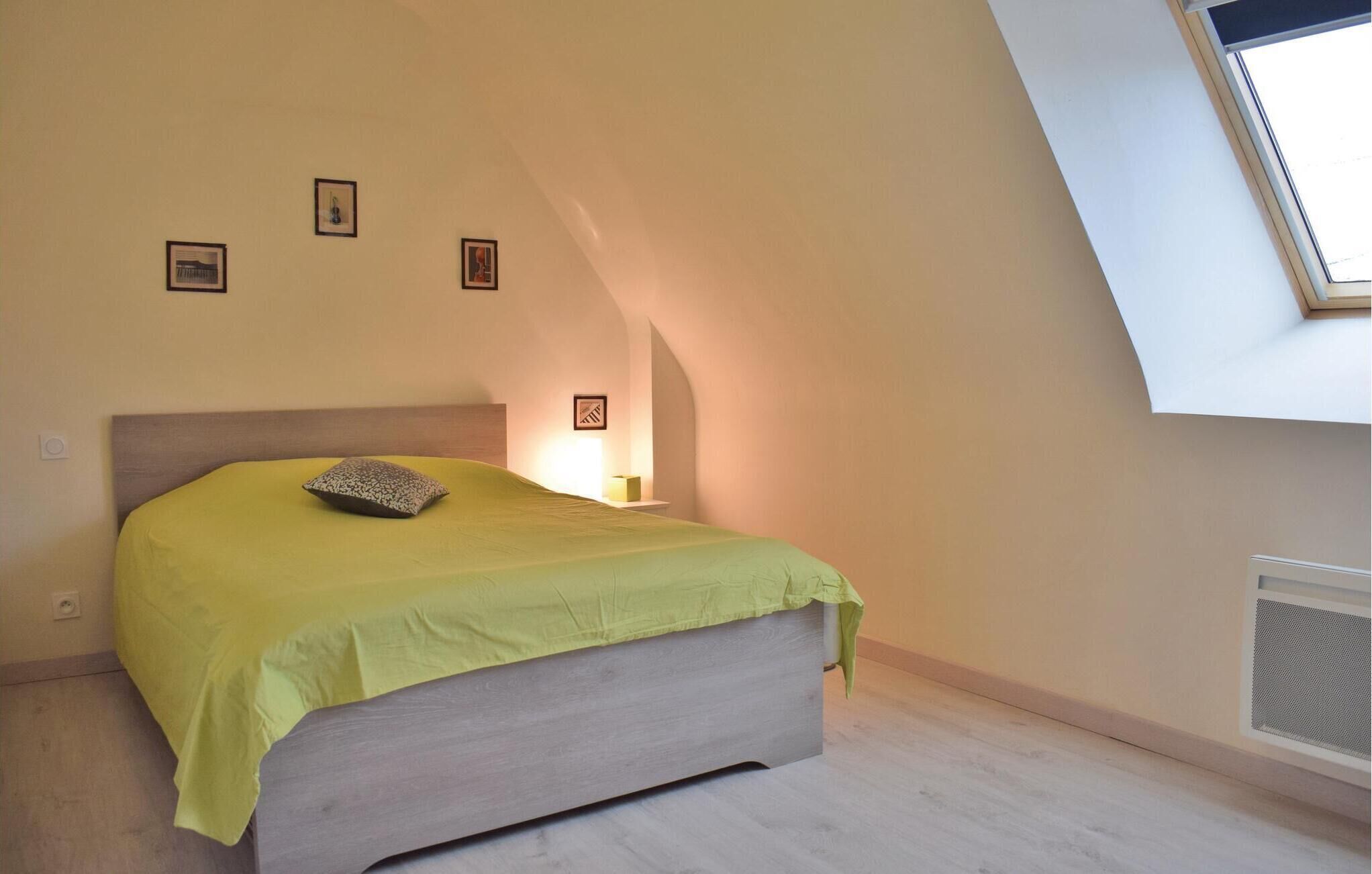 A bedroom with a bed, a skylight, and a small bedside table with a lamp.