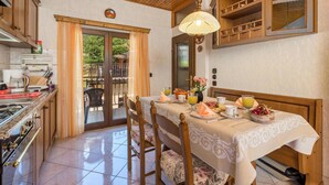 Un comedor con una mesa lista para el desayuno, una cocina con electrodomésticos modernos y vistas a un patio exterior a través de un ventanal.