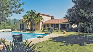 Ein Haus mit Swimmingpool, Palmen und einem gepflegten Rasen.