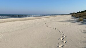 Ein Sandstrand mit Fußspuren, die zum Meer führen.