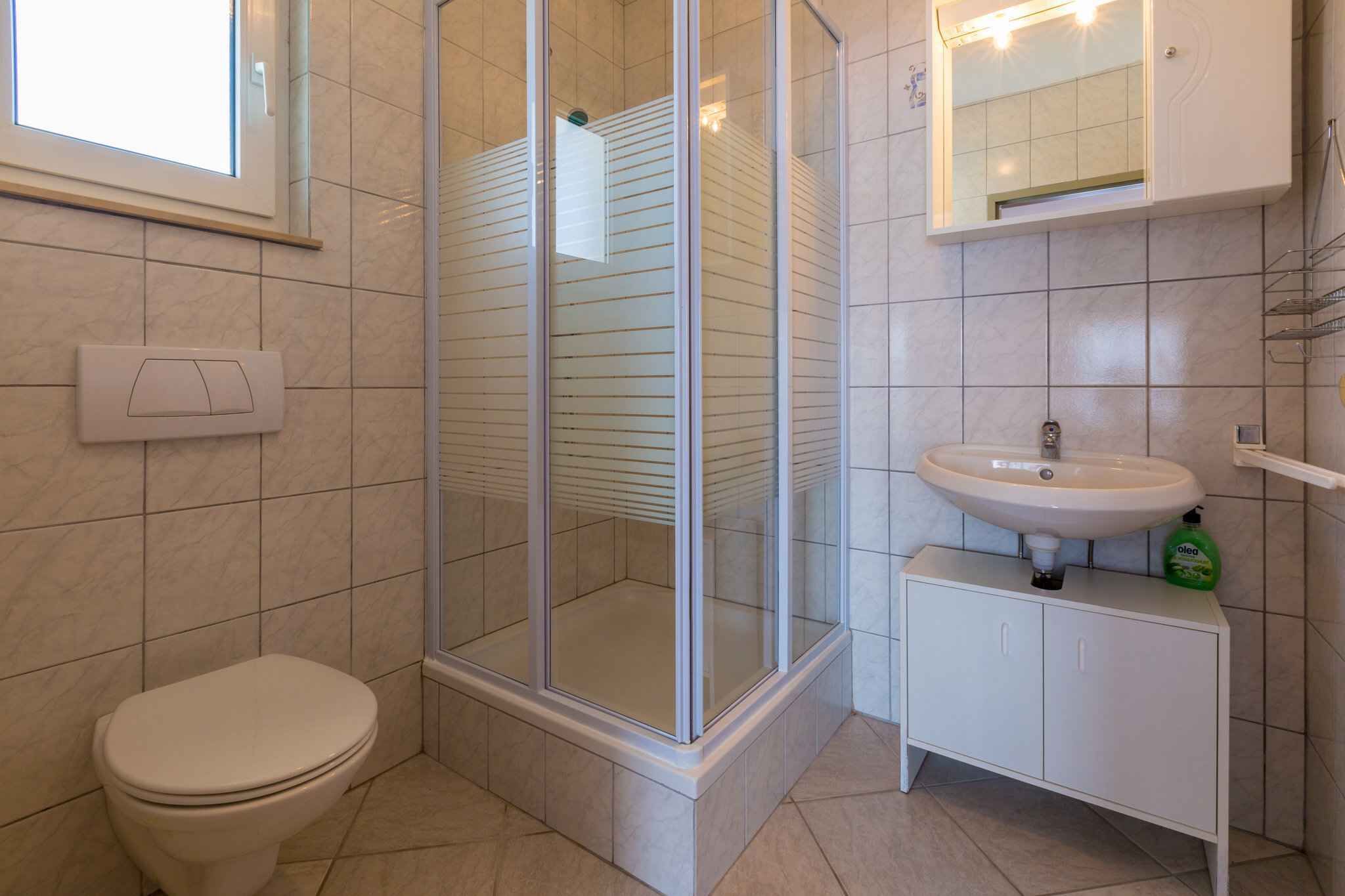 A bathroom with a toilet, a glass-enclosed shower, and a sink with a mirror above it.