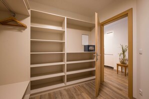 A walk-in closet with multiple shelves, a wooden floor, and a door leading to another room. - Apartment Mountain Deluxe - Aparthotel **** AlpTirol (Kaltenbach)